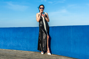 Senior model enjoying a refreshing drink on a rooftop with blue wall
