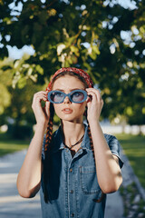 Lifestyle woman in modern boho-western denim street style adjusting blue sunglasses outdoors with...