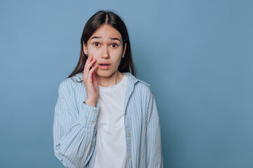 young woman displays a concerned look with her hand on her face, conveying feelings of worry or...