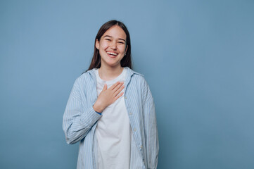 young woman with a warm smile places her hand on her heart, exuding kindness and sincerity on light...