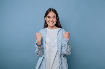 energetic young woman expressing joy with her fists raised, capturing celebration and triumph on...