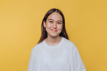 bright smile radiates from a youthful woman posing casually on vibrant yellow background