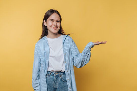 young woman extending her hand in a friendly gesture on vibrant yellow background