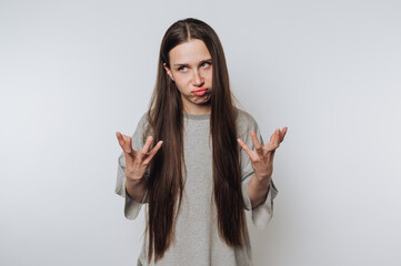 young woman with a frustrated expression and raised hands portrays confusion on white background