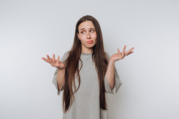 bewildered woman shrugs her shoulders with an unsure expression on white background