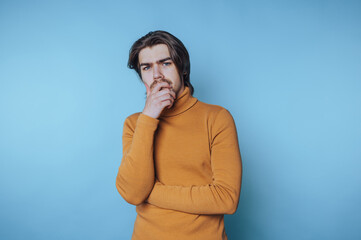 young man stands with a thoughtful pose, hand on chin, reflecting on profound ideas and concepts on...