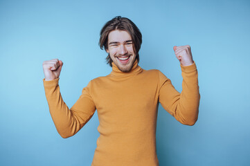 young man celebrates with raised fists and an enthusiastic smile, radiating positive energy and joy...