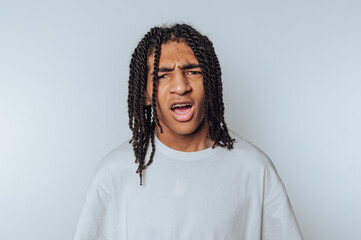 young man displays frustration and confusion with a raised brows and open mouth on white background