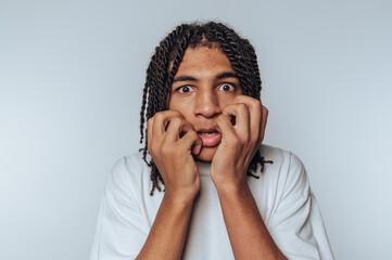 young person shows a scared expression, with hands gripping their face on white background