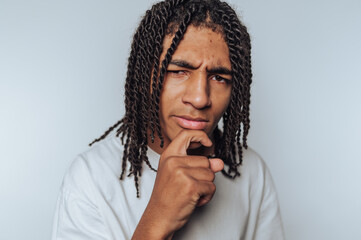 young man displays a thoughtful expression and gesture, as if deep in a pondering moment,...