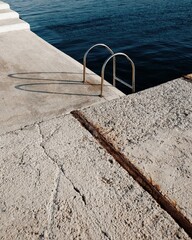 Harbor ladder with curved shadow at the edge of the sea in aegina, greece – abstract textures and...