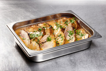 Slices of tender roast meat are arranged in a stainless steel tray, covered in a rich, savory sauce and garnished with fresh herbs. Perfect for a hearty meal