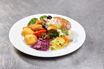 A vibrant plate showcases grilled chicken, broccoli, carrots, and a variety of vegetables, garnished with herbs, highlighting a well-prepared meal