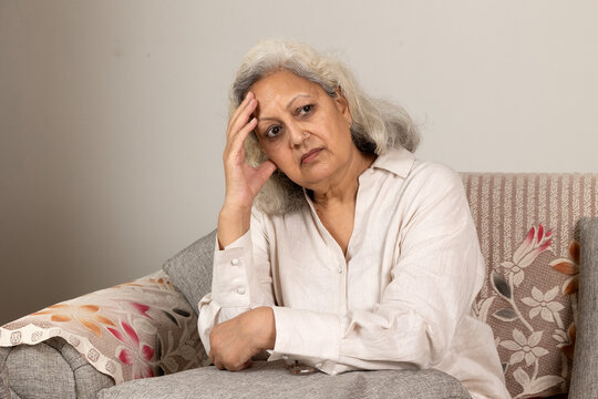 Indian sad  and depressed senior woman grandmother sitting on the wooden chair at home.  bankruptcy, Sad elder female tired ill sick lonely disappointed, pain, and fraud at home