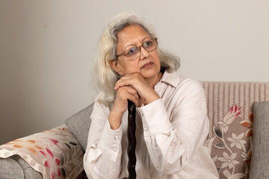 Indian sad and depressed senior woman grandmother sitting on the wooden chair at home. bankruptcy, Sad elder female tired ill sick lonely disappointed, pain, and fraud at home