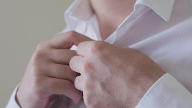 The man in the white shirt is buttoning up his shirt