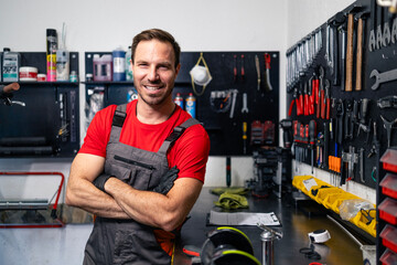 Portrait of experienced caucasian serviceman holding arms crossed and standing in bicycle repair...