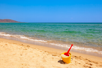 Colorful beach toys on sand near calm sea during sunny summer day