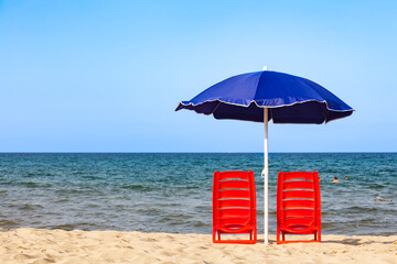 Beach chairs and umbrella on sandy beach facing sea