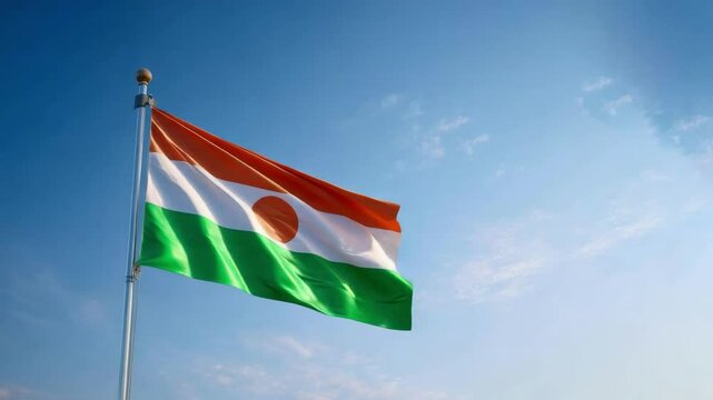 The Niger flag, with its orange, white, and green colors and central circle, waves against a bright blue sky on Independence Day. - Powered by Adobe