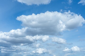 Clear blue sky background showcasing large fluffy white clouds and scattered grey cloud formations