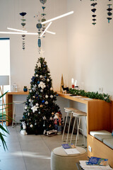 Cozy christmas café corner with decorated tree and festive ornaments beneath hanging mobiles