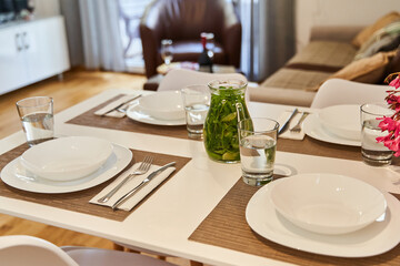 Elegant dining table setup with glass jars and cutlery in modern living room
