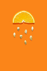 Creative food health diet concept photo of orange slice with seeds falling down like rain on orange background.