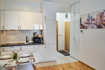 Modern white kitchen and dining space with minimalist decor and art