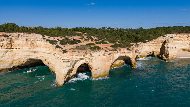 Aerial view of rugged cliffs meet the turquoise sea, sculpted by time and tide near Algar Seco, a symphony of nature's artistry, Lagoa, Faro District, Portugal.