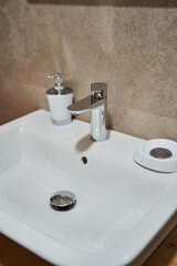 Modern white ceramic bathroom basin with chrome faucet and soap dispenser