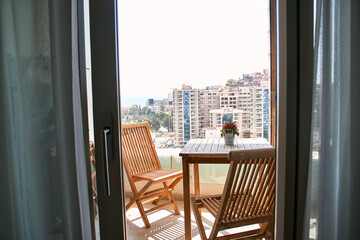 City balcony view with wooden outdoor furniture and urban landscape in daylight
