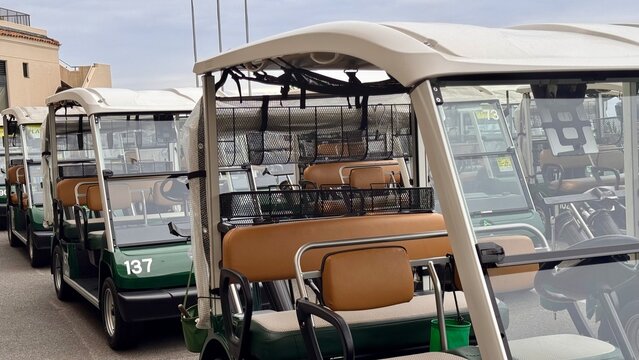Some golf carts in green colour standing in a row without people outdoor at daytime at a golf resort in Fukushima in Japan.