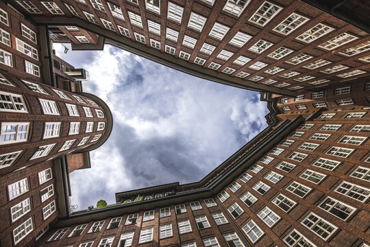 View of historic brick buildings rise dramatically towards a patch of cloudy sky, creating a compelling architectural perspective, Hamburg, Hamburg, Germany.