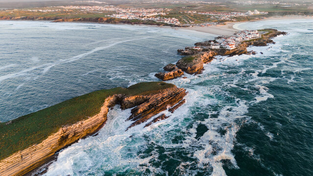 Aerial view of the rugged Baleal peninsula, where the wild Atlantic crashes against rocky cliffs and sandy shores, Baleal, Leiria District, Portugal.