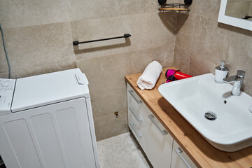Modern bathroom with washing machine and wooden countertop sink area