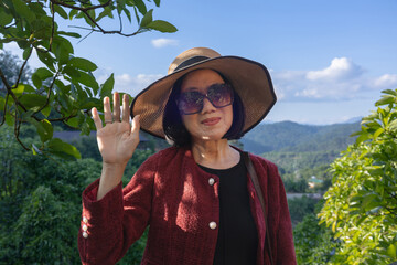 A senior Asian woman is using her phone, call, text or video call. Travel, enjoy life, Green life...