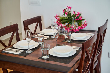 Elegant dining table setting with flowers and four place settings in a modern home