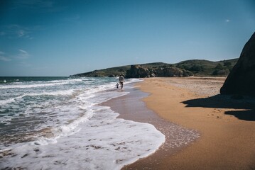 father and son walking along an empty beach by the sea