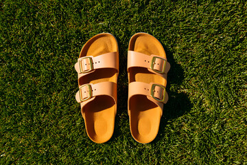 Stylish sandals sit on lush green grass, soaking up the warm sunlight of a sunny afternoon in summer