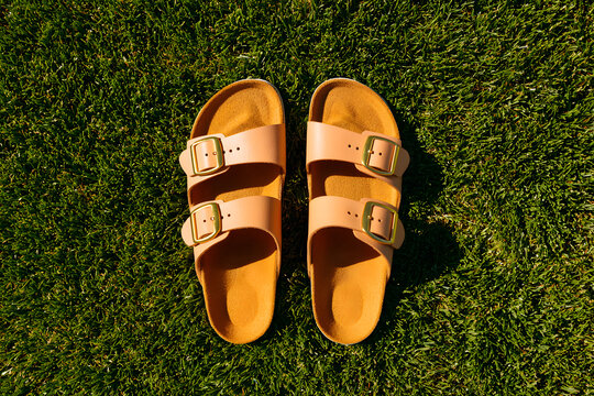 Stylish sandals sit on lush green grass, soaking up the warm sunlight of a sunny afternoon in summer
