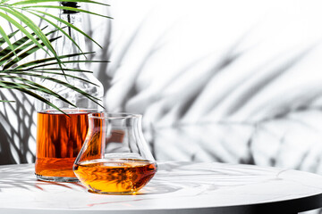 Japanese single malt whiskey glass next and bottle, with decorative plant shadows creating a...