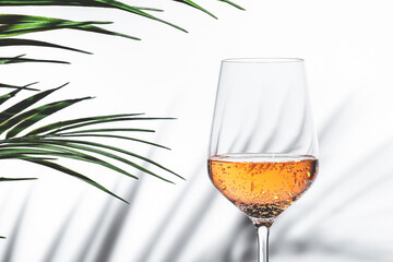 Refreshing rose pink wine served in a elegant glass surrounded by green leaves perfect for...