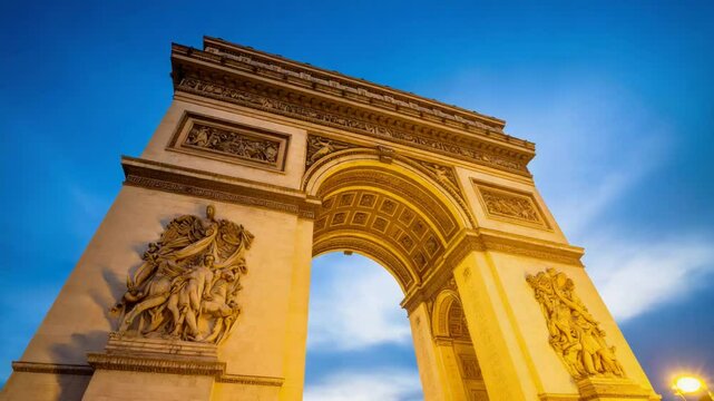 Majestic arc de triomphe in paris bathed in golden light under a clear blue sky at dusk