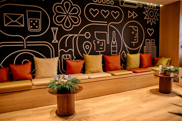 Modern lounge with colorful cushions and graphic mural wall design in cozy seating area © Lui Shtein