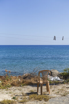 View of a solitary chair sits near a clothesline with clothespins, overlooking the tranquil turquoise sea under a bright blue sky, Dipkarpaz, Northern Cyprus, Cipro.
