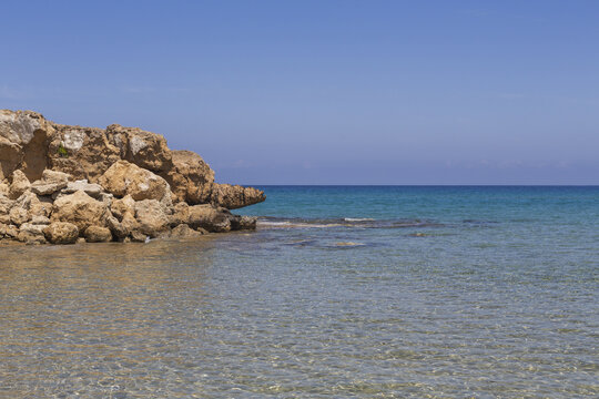 View of rocky coastline meets the turquoise sea under a clear blue sky, creating a tranquil scene of natural beauty, Dipkarpaz, Northern Cyprus, Cipro.