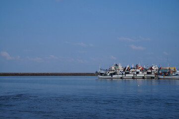 Obraz premium Fishing boats moored at a peaceful harbor under a clear summer sky