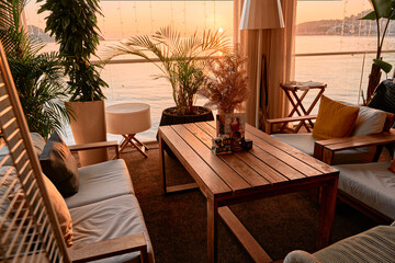 Cozy balcony sunset view with comfortable seating and plants by the water
