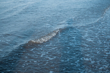 Obraz premium Multiple layers of ocean waves rolling towards the shore under a clear sky, showcasing the dynamic power and beauty of the sea.